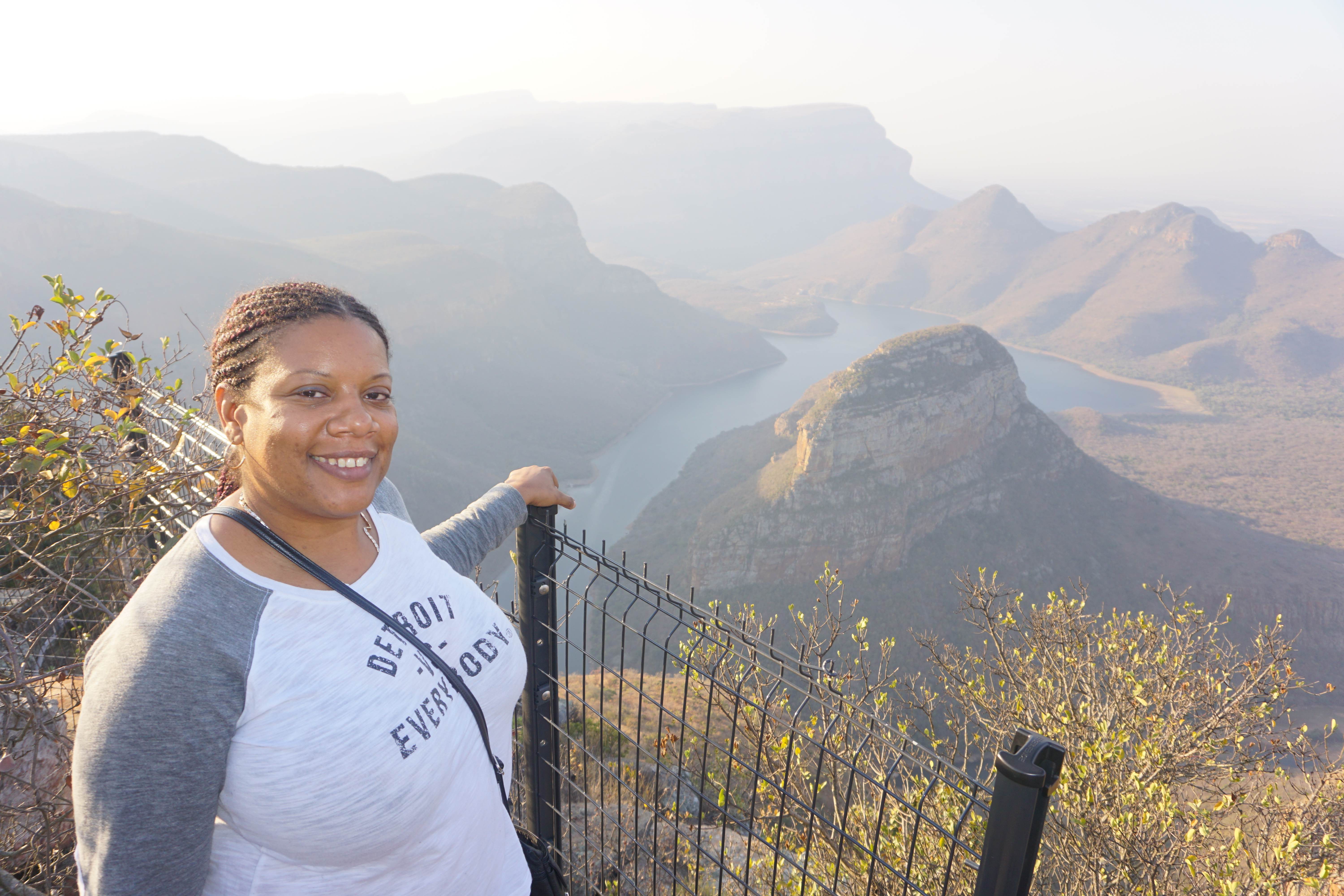 A traveler smiling at a mountain overlook above the Blyde River Canyon in South Africa